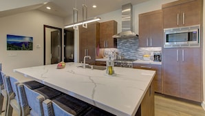 A modern kitchen with a large island, stainless steel appliances, and wooden cabinets. - Juniper Landing 3 Bedroom by Avantstay Condo in Park City Mountain Resort w/ Pool, Hot Tub & Gym (Park City)