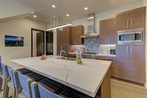 A modern kitchen with a large island, stainless steel appliances, and wooden cabinets. - Juniper Landing 3 Bedroom by Avantstay Condo in Park City Mountain Resort w/ Pool, Hot Tub & Gym (Park City)