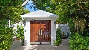Un petit bâtiment blanc, avec une porte en bois et un toit blanc.