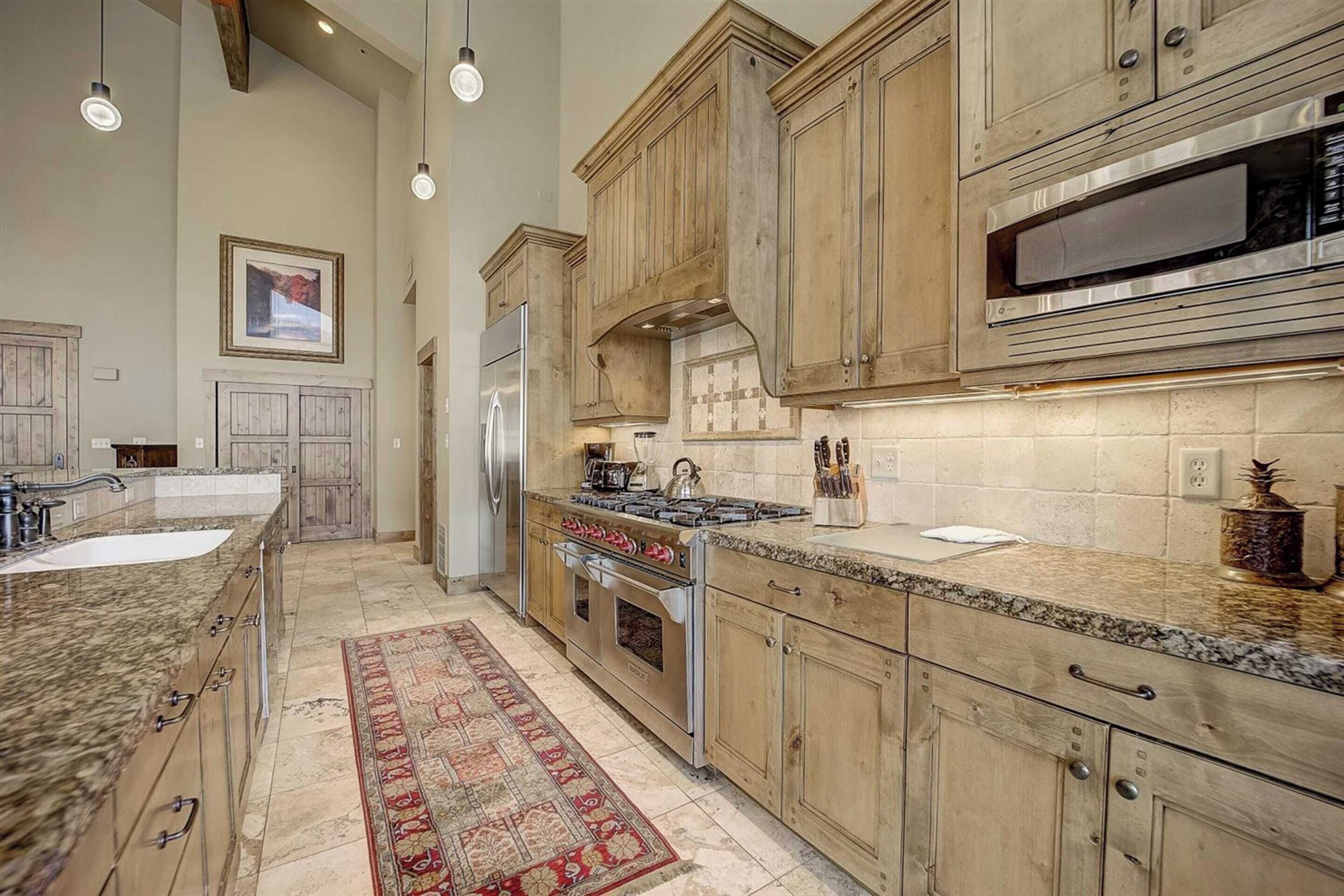 A kitchen with wooden cabinets, a stainless steel refrigerator, a built-in oven, and a microwave.