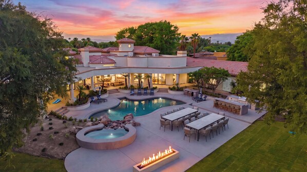 Un resort moderno con piscina, mobiliario exterior y una chimenea.