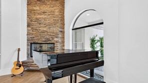 A modern interior with a piano, a guitar, and a stone fireplace. - Villa Verbena by Avantstay Expansive Estate w/ B-ball Court, Pool/spa & Entertainer's Yard (Indio)
