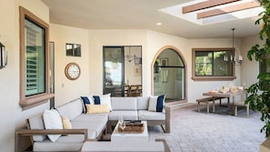 A modern outdoor living area with a sofa, dining table, and chairs, connected to a covered patio. - Villa Verbena by Avantstay Expansive Estate w/ B-ball Court, Pool/spa & Entertainer's Yard (Indio)