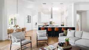 A spacious living room with a sofa, chairs, a coffee table, and a kitchen in the background. - Villa Verbena by Avantstay Expansive Estate w/ B-ball Court, Pool/spa & Entertainer's Yard (Indio)