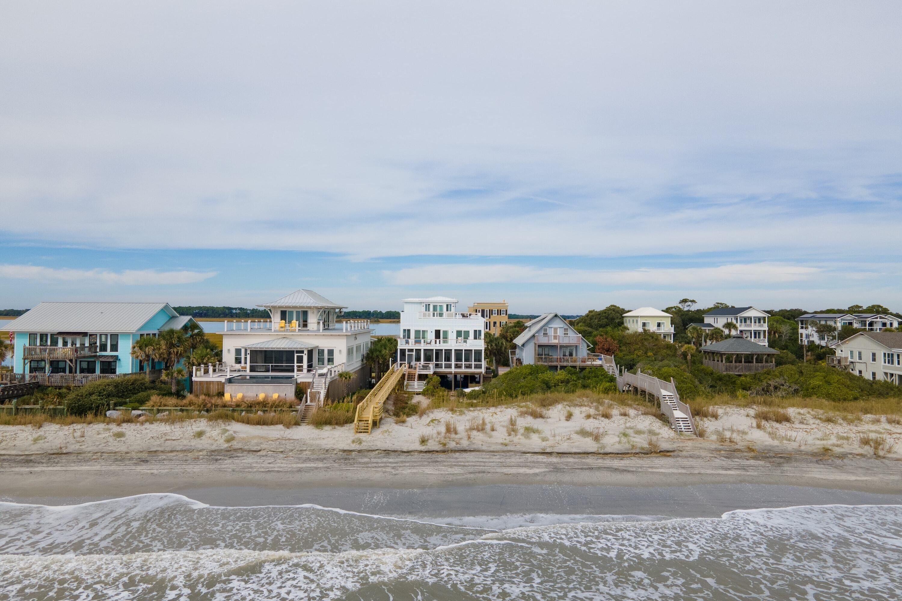 A beachfront property with multiple houses, a sandy beach, and a staircase leading to the beach.