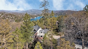 Une maison entourée d’arbres, avec vue sur les montagnes et un lac.
