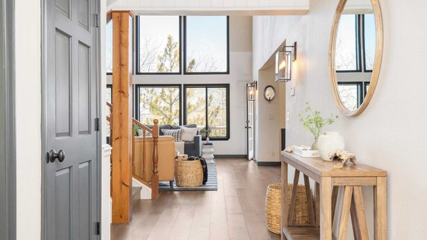 Ein geräumiger Flur mit einer Holztreppe, großen Fenstern und einem rustikalen Holztisch mit Dekoration.