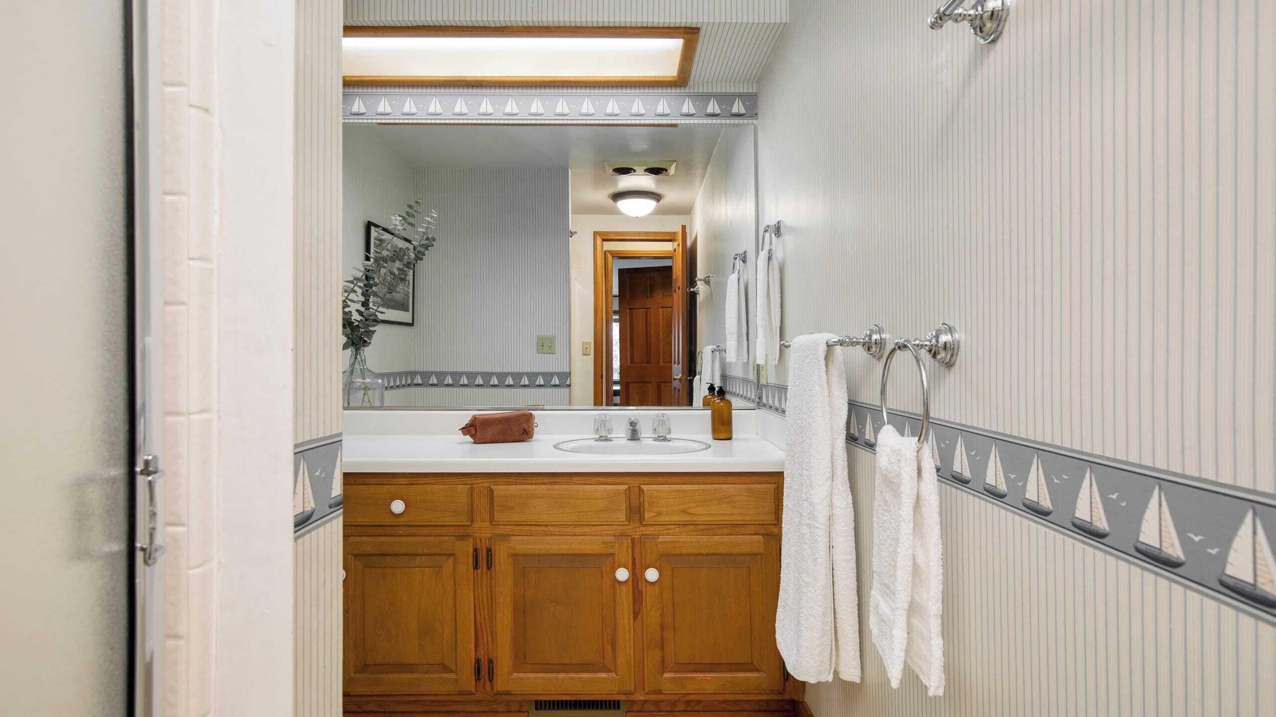 Un baño con tocador de madera, espejo y perchero para toallas.