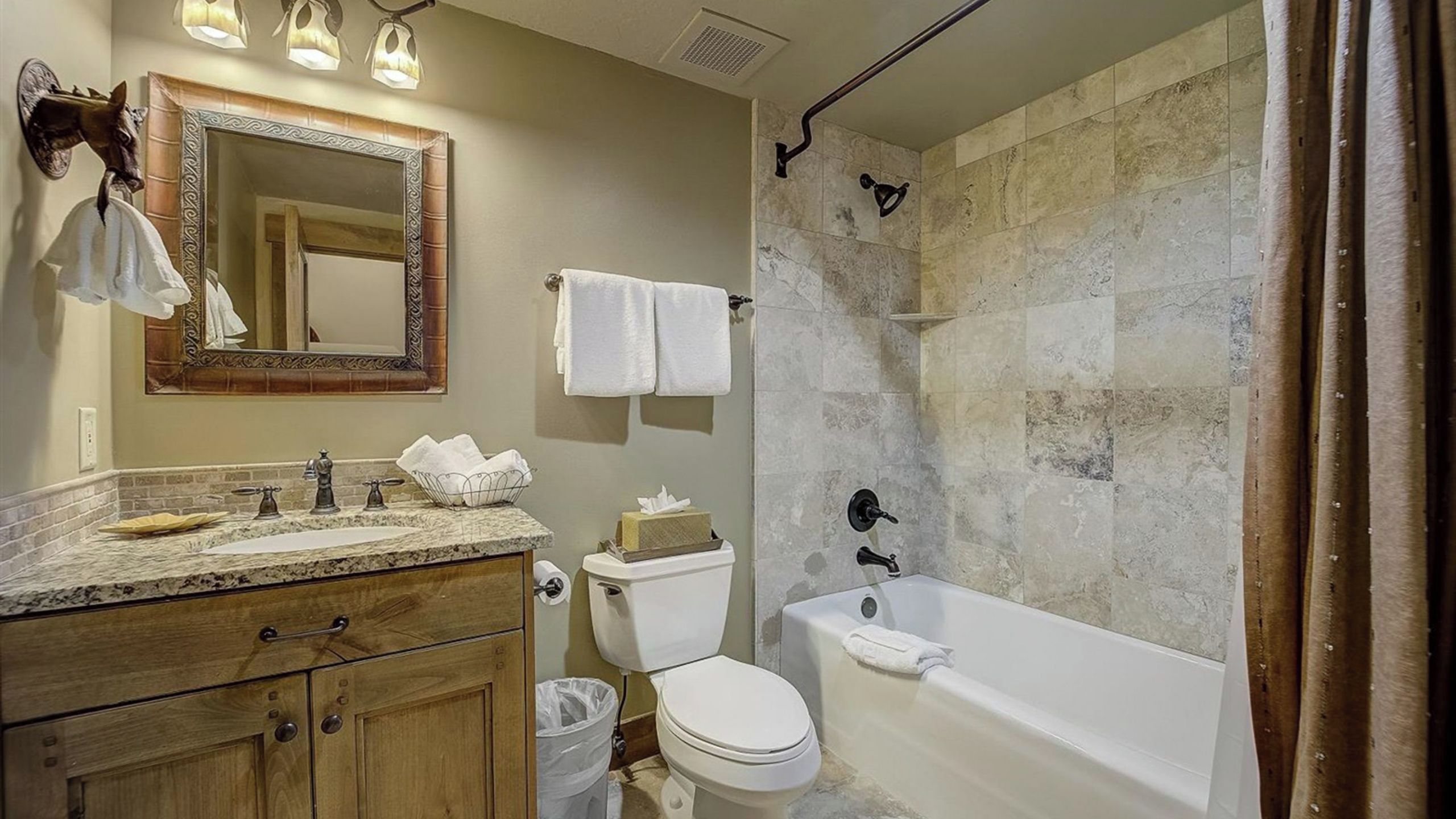A bathroom with a marble sink, a toilet, a bathtub, and a shower with a stone wall.