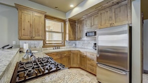 A kitchen with wooden cabinets, a stainless steel refrigerator, a gas stove, and a microwave. - Mont Cervin #22 by Avantstay Luxury Ski in Ski out Home in Park City! (Park City)