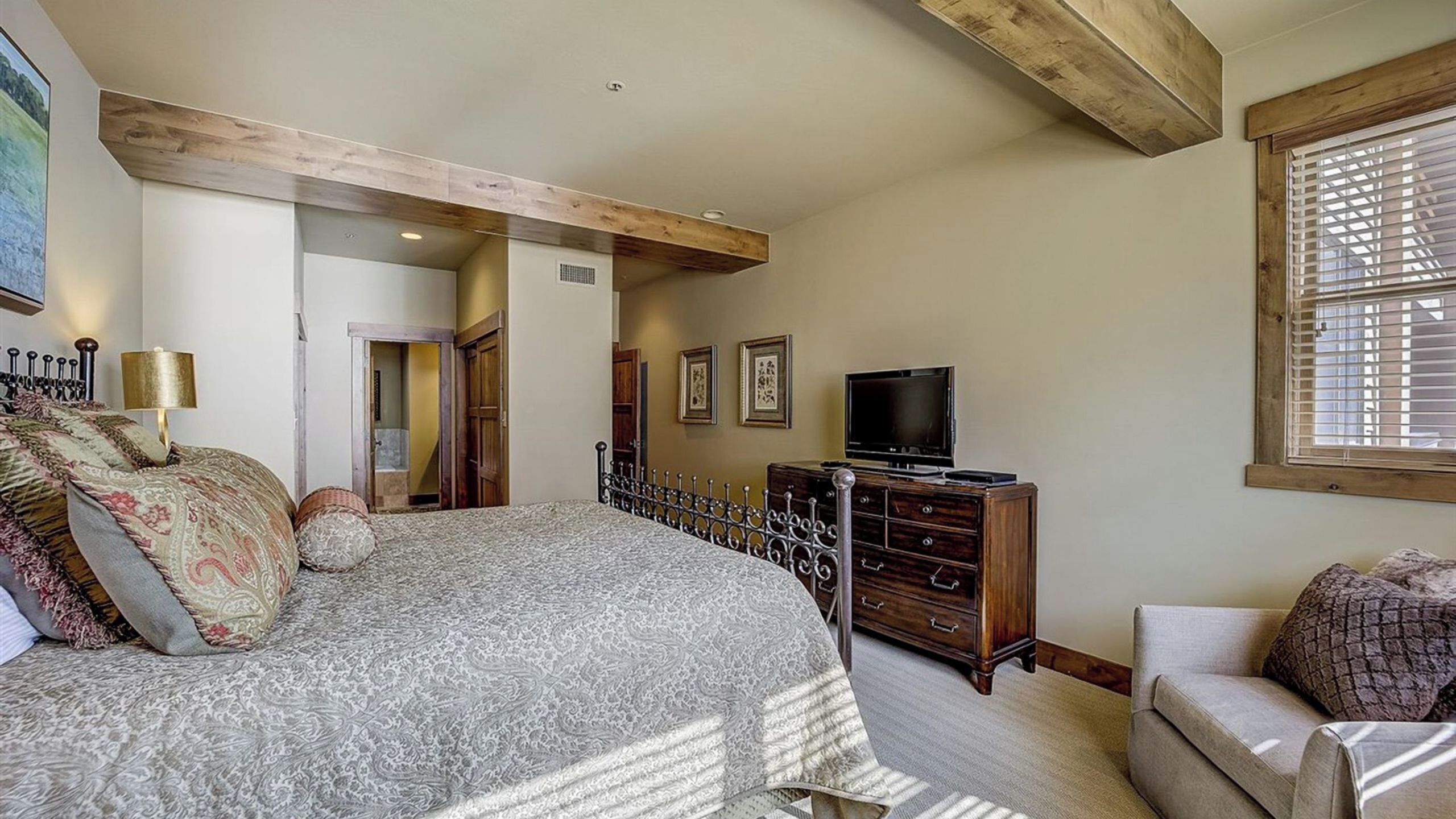 Un dormitorio con cama, cómoda, televisor y ventana.
