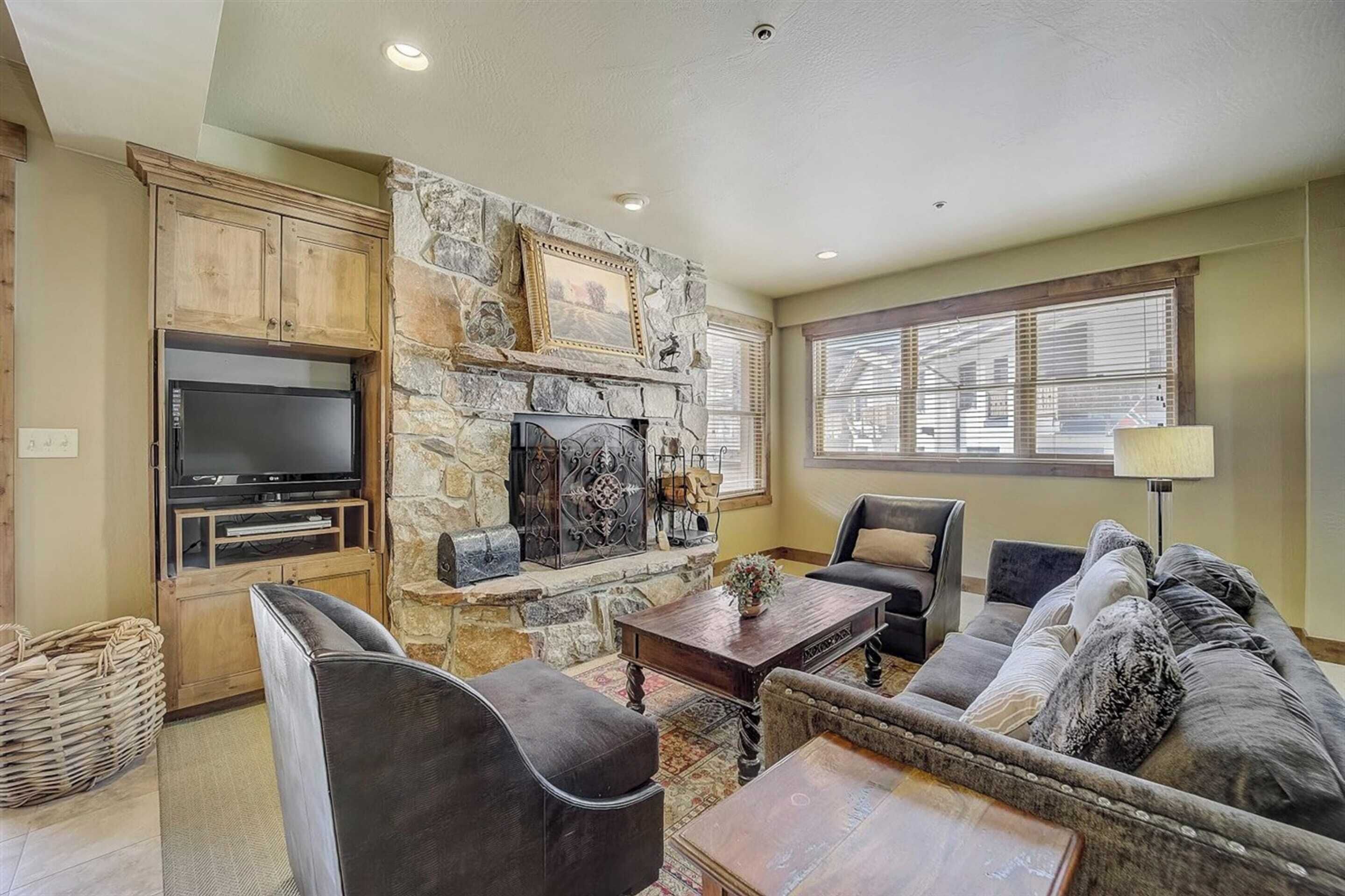 A living room with a stone fireplace, a flat-screen TV, a sofa, and a coffee table.