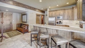 A kitchen with wooden cabinets, a marble countertop, and three bar stools. - Mont Cervin by Avantstay Private Hot Tub + Fireplace Walk to Ski-in/ski-out + Dining (Park City)