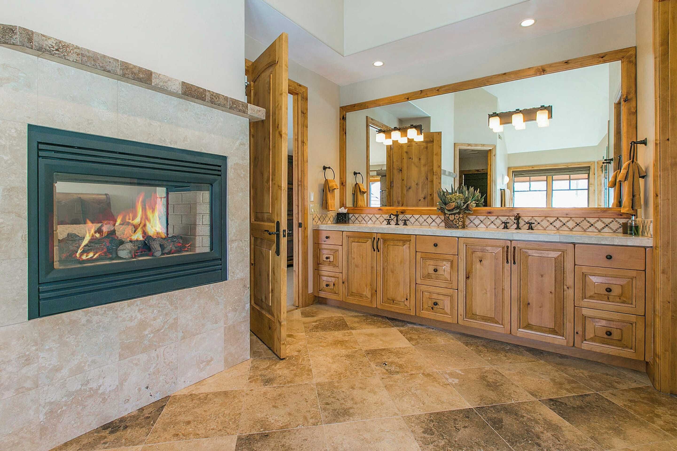 A kitchen with a fireplace, wooden cabinets, and a large mirror.