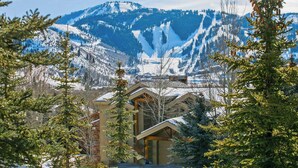 A lodge with a wooden exterior, surrounded by snow-covered mountains and evergreen trees.