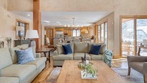 A spacious living area with a large sofa set, a wooden coffee table, and a chandelier.