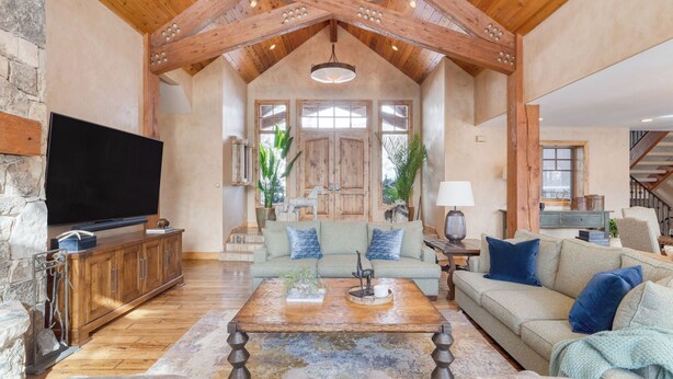A spacious living room with a wooden ceiling, a television, a sofa, and a coffee table.