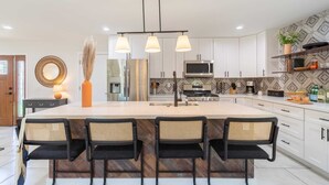 A modern kitchen with a large island, white cabinetry, and a herringbone tile backsplash. - Rosario by Avantstay10mins to Old Town Scottsdale (Scottsdale)