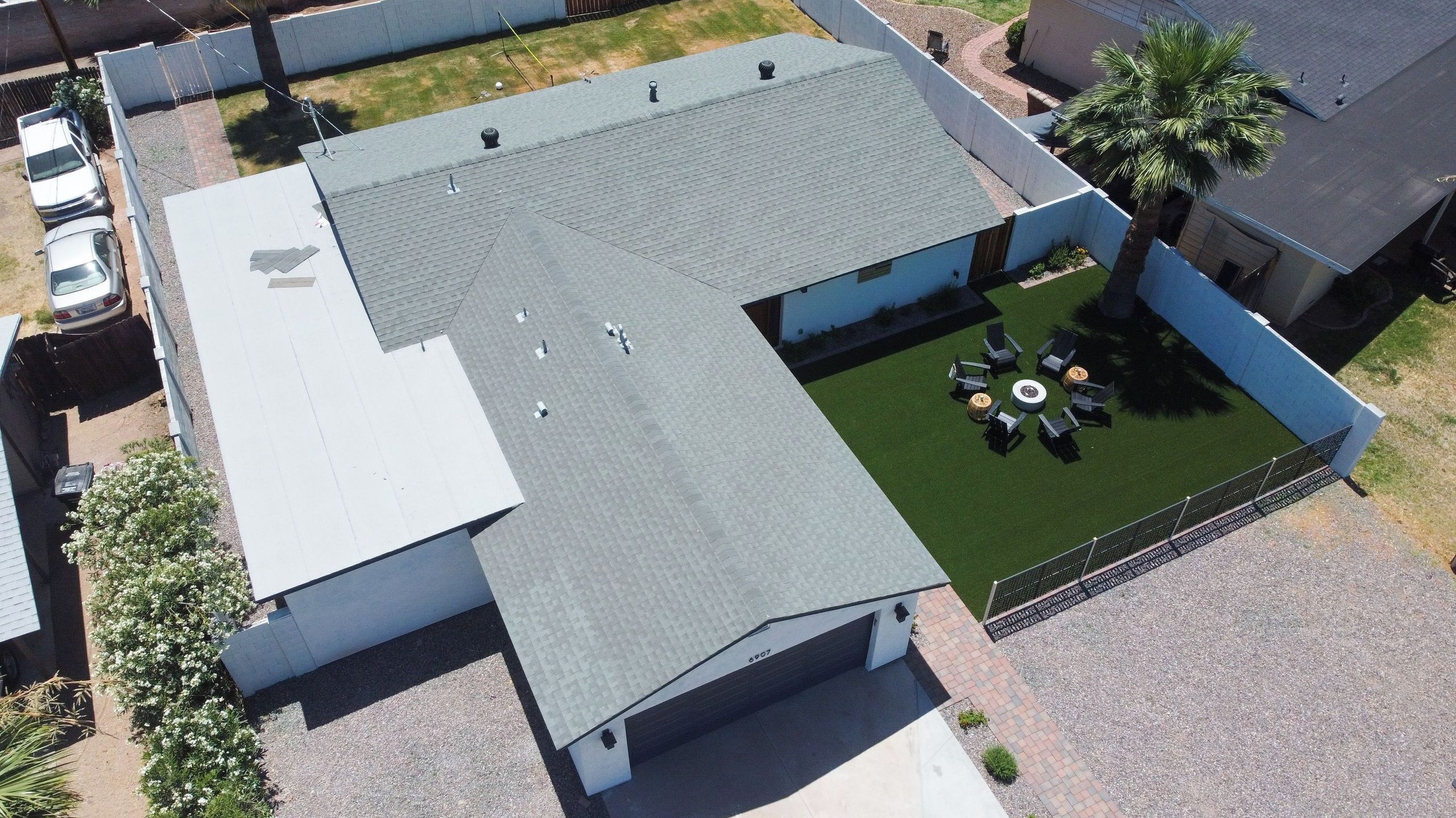 Luchtbeeld van een gebouw met een plat dak, een omheind buitengebied met een ronde zithoek, en een garage met een zichtbaar nummer.