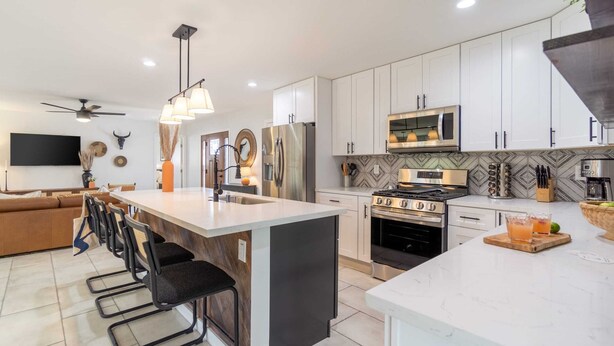 A modern kitchen with white cabinets, stainless steel appliances, and a central island with bar stools. - Rosario by Avantstay10mins to Old Town Scottsdale (Scottsdale)