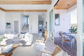 A modern interior with a living area, dining space, and a staircase leading to another level. - Rendezvous by Avantstay Modern Haven w/ Game Room, Roof Top, Pool & Close to Beach! (Miramar Beach)