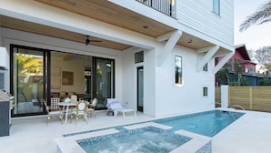 A modern house with a swimming pool, a covered patio with outdoor furniture, and a large sliding glass door leading to an interior space. - Rendezvous by Avantstay Modern Haven w/ Game Room, Roof Top, Pool & Close to Beach! (Miramar Beach)