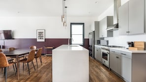 Una cocina moderna con una isla central, electrodomésticos de acero inoxidable y un comedor con sillas de madera.