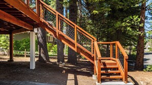 A wooden staircase with a metal railing, surrounded by trees.