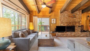 A cozy living room with a fireplace, a sofa, a television, and a ceiling fan. - Fawn by Avantstay Secluded Cabin w/ Large Deck Surrounded by Forest (Tahoma)