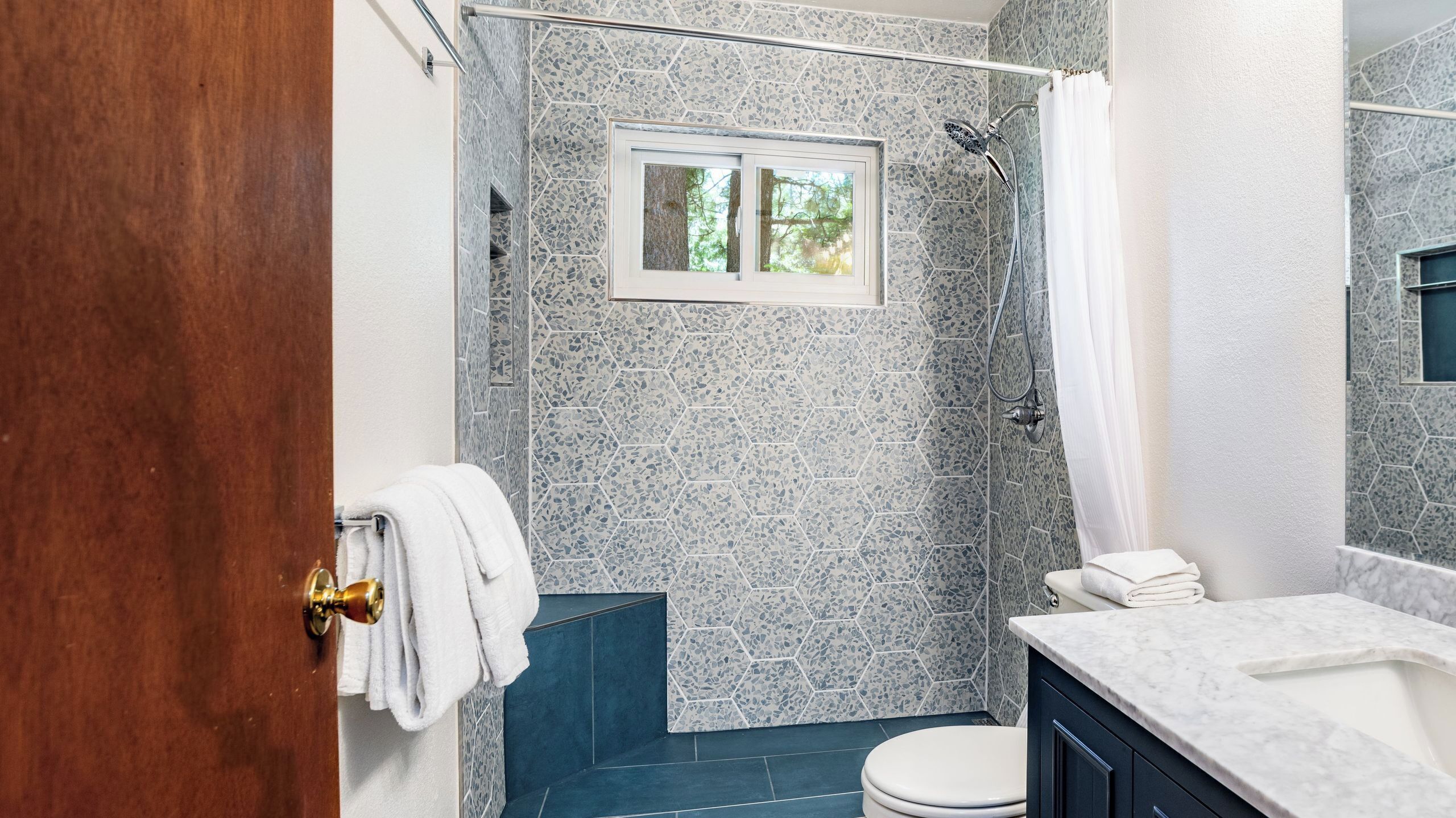 Ein Badezimmer mit Dusche, Toilette, Waschbecken und Fenster.