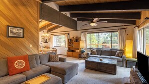 A cozy living room with a sofa, ottoman, coffee table, and a ceiling fan.