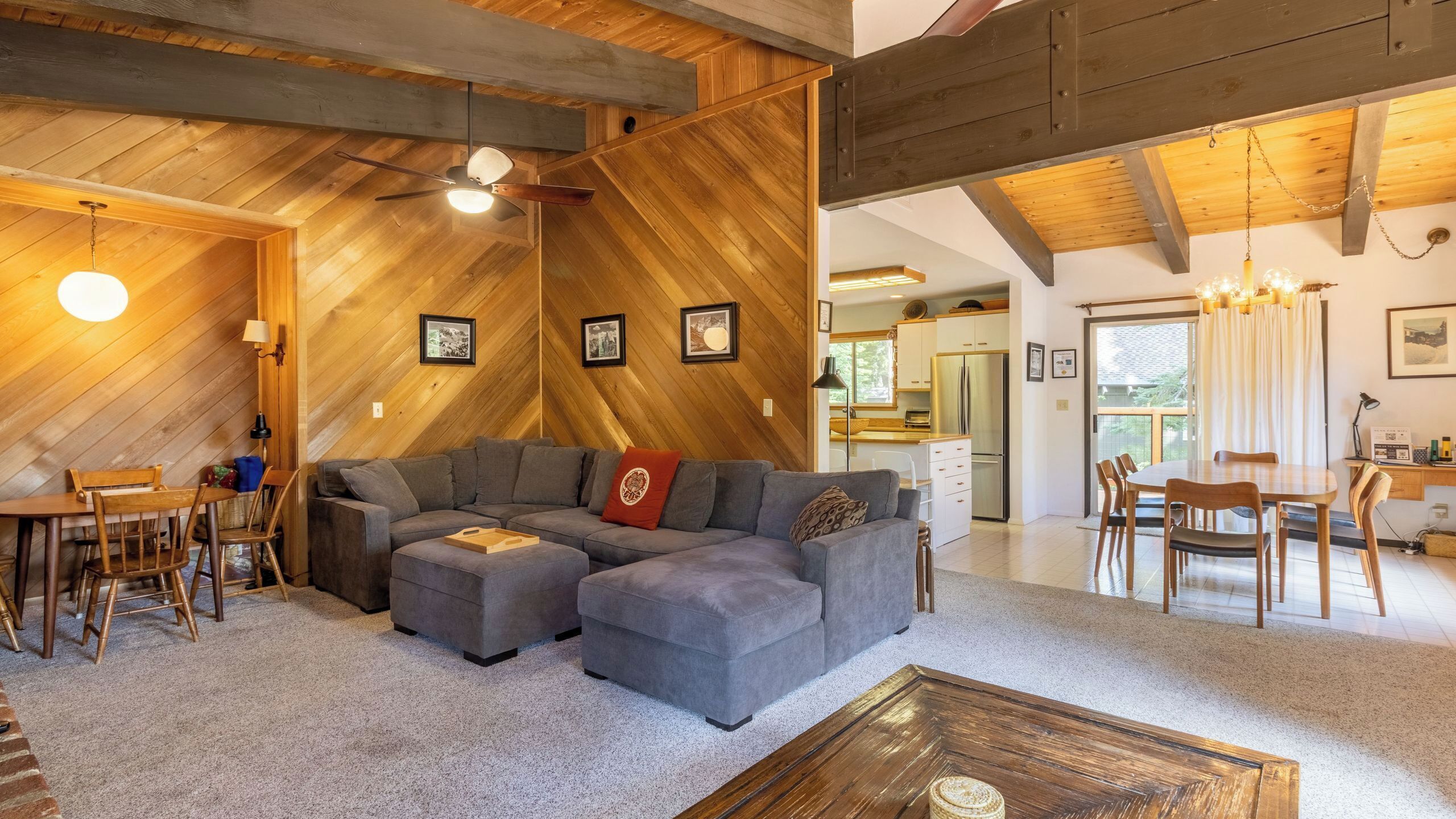 A cozy living room with a sectional sofa, a coffee table, and a dining area with chairs and a table.