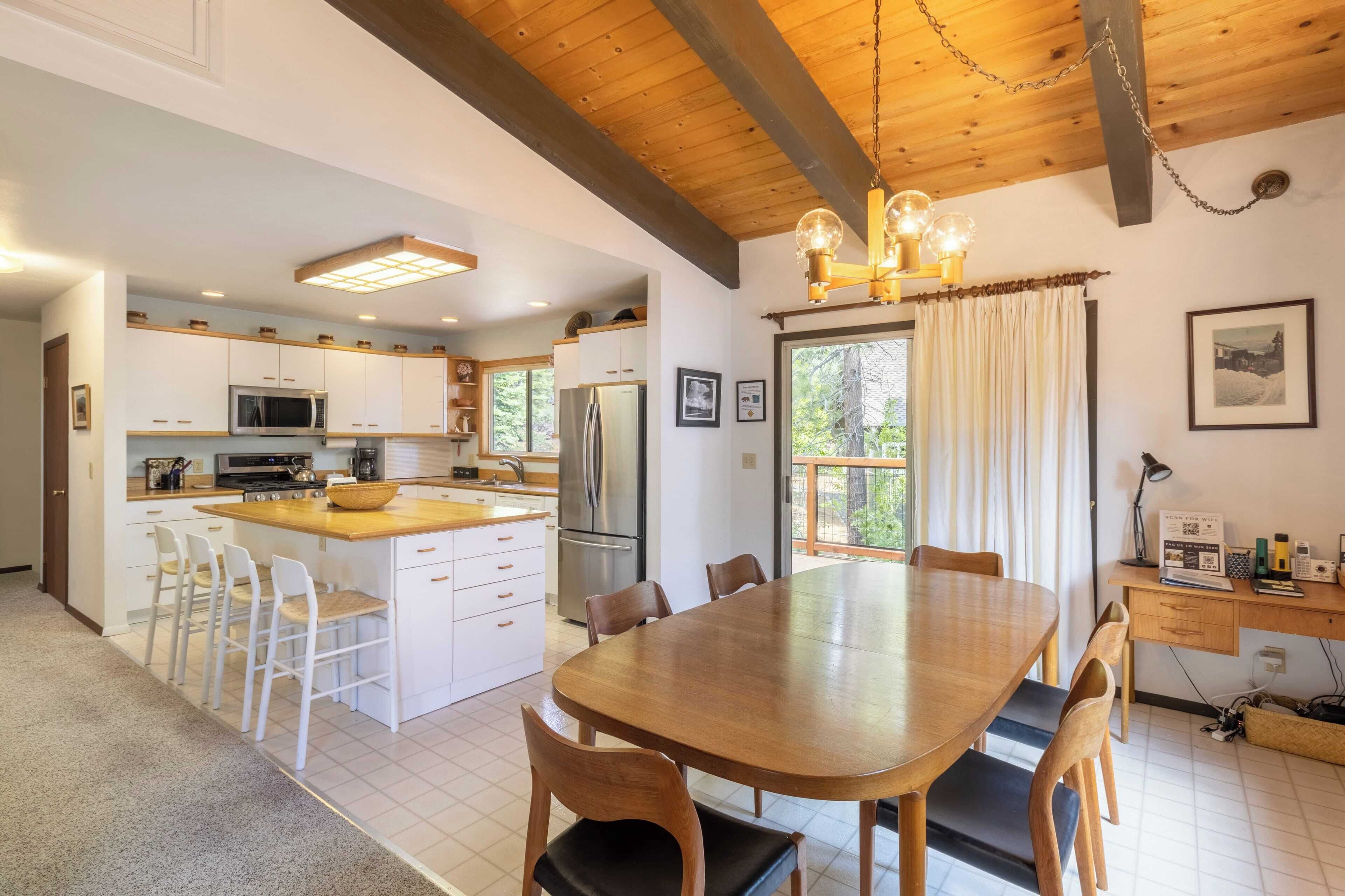 A spacious kitchen with white cabinets, a wooden dining table, and a large island with stools.
