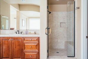 A bathroom with a glass shower enclosure, wooden cabinets, and a large mirror. - Desert Grove by Avantstay Oasis Retreat w/ Pool & BBQ Grill! (Indio)