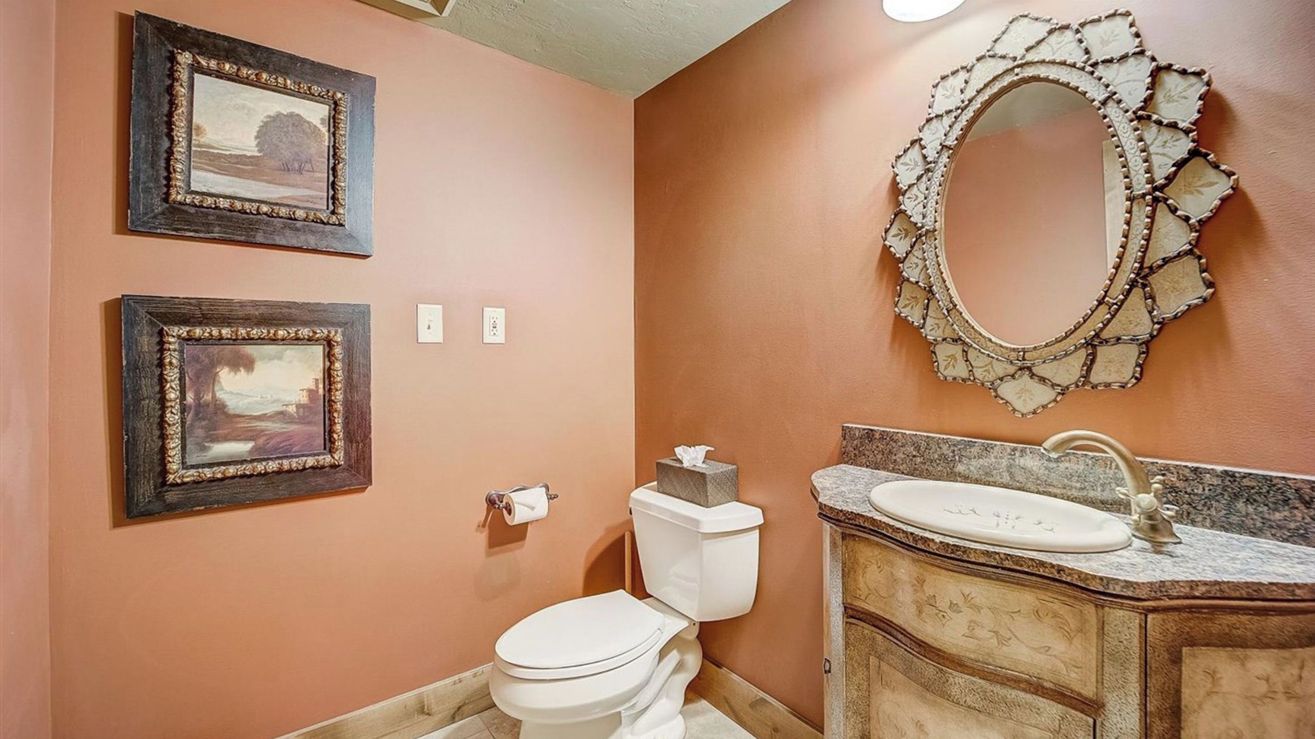 Une salle de bain avec des toilettes, un lavabo et deux tableaux encadrés accrochés au mur.