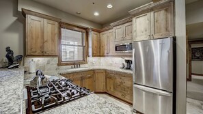 A kitchen with wooden cabinets, a stainless steel refrigerator, a gas stove, and a microwave. - Mont Cervin #24 by Avantstay Luxury Ski in Ski out Home in Park City! (Park City)