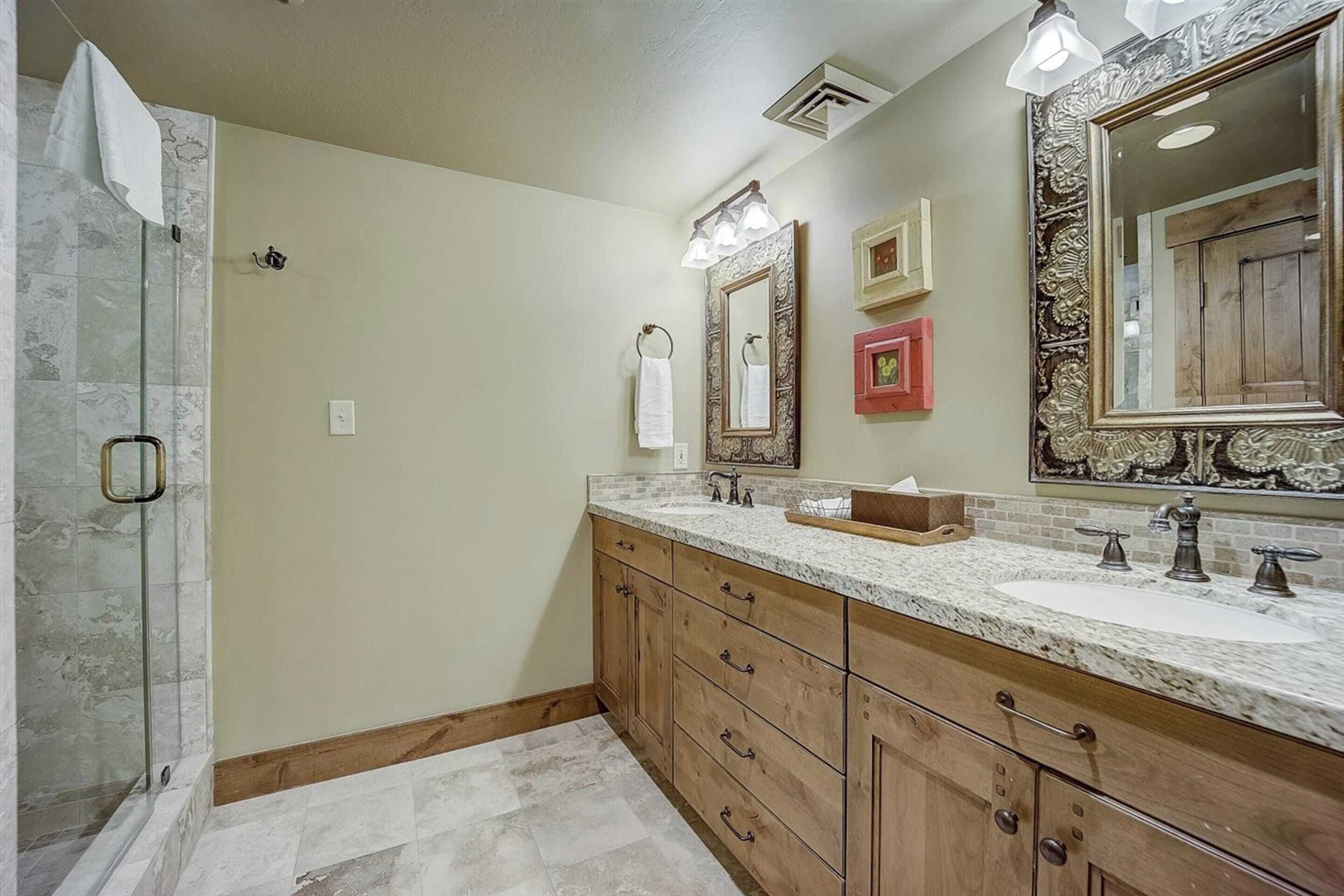 A bathroom with a large mirror, a sink, and a shower.