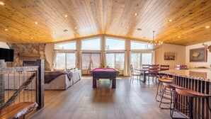 A spacious room with a pool table, a bar area, and large windows providing natural light. - Lakefront Lodge by Avantstay Direct Access to Big Bear Lake Hot Tub + Views (Big Bear Lake)
