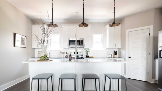 A modern kitchen with white cabinets, a central island with bar stools, stainless steel appliances, and pendant lighting. - Chesney by Avantstay Contemporary East Nashville Home w/ Southern Flare (Nashville)