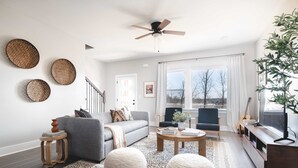 A modern living room with a grey sofa, round ottomans, a coffee table, and a TV stand. - Chesney by Avantstay Contemporary East Nashville Home w/ Southern Flare (Nashville)
