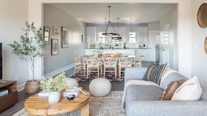 A modern living room with a sofa, coffee table, and a dining area with a table and chairs. - Chesney by Avantstay Contemporary East Nashville Home w/ Southern Flare (Nashville)
