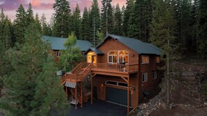 A two-story cabin with a balcony, surrounded by dense forest. - Golden Summit by Avantstay Stunning Secluded Cabin w/ Access to Tahoe Donner (Truckee)