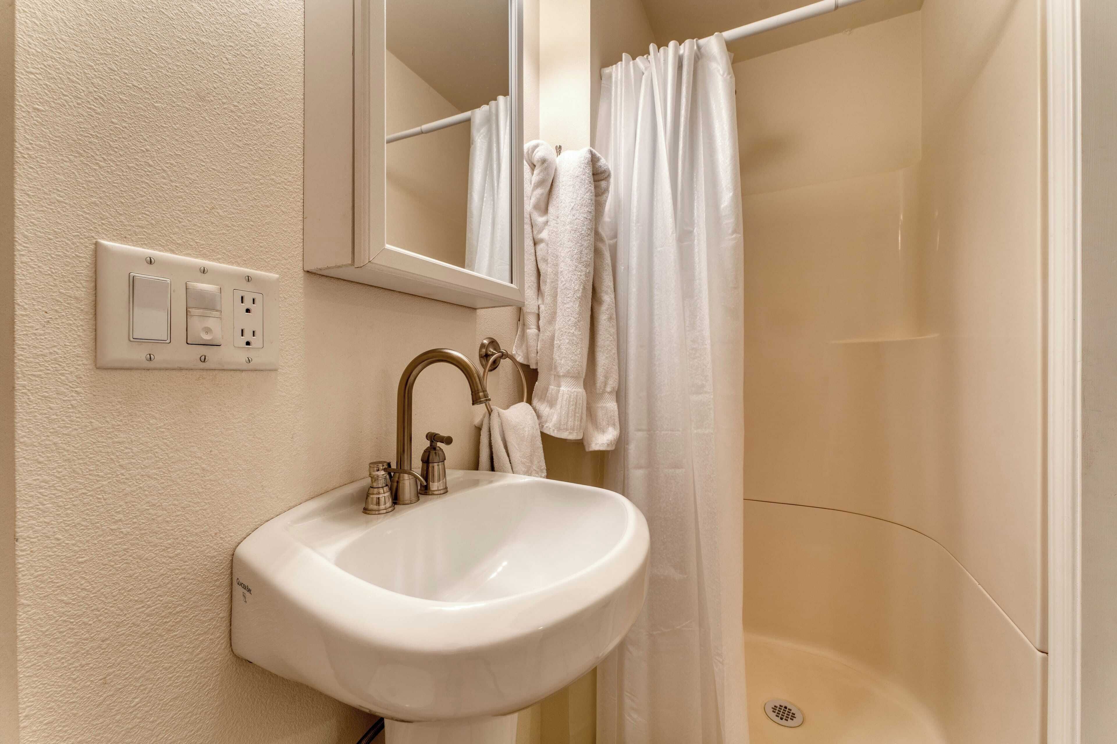 A bathroom with a white sink, a mirror, a towel, and a shower curtain.