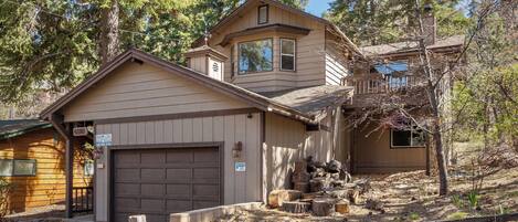A two-story building with a garage, a small porch, and a wooden fence.