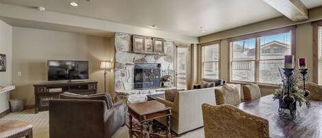 A living room with a stone fireplace, a television, and a dining area with a table and chairs.