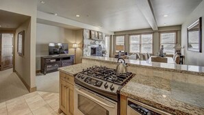 A spacious kitchen with granite countertops, a built-in stove, and a large window overlooking the living area. - Mont Cervin by Avantstay Condo w/ Hot Tub + Jetted Tub + Fireplace Ski-in/ski-out (Park City)