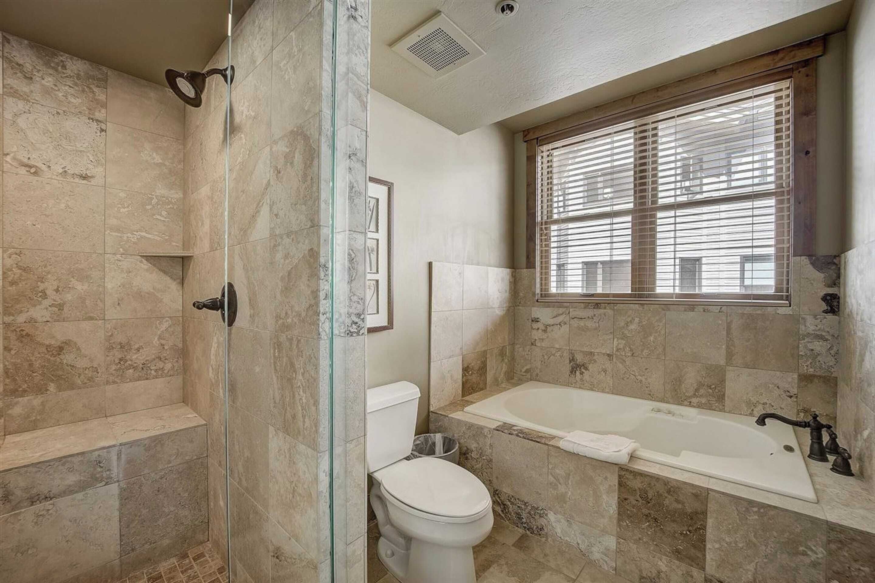 A bathroom with a glass-enclosed shower, a toilet, and a bathtub.