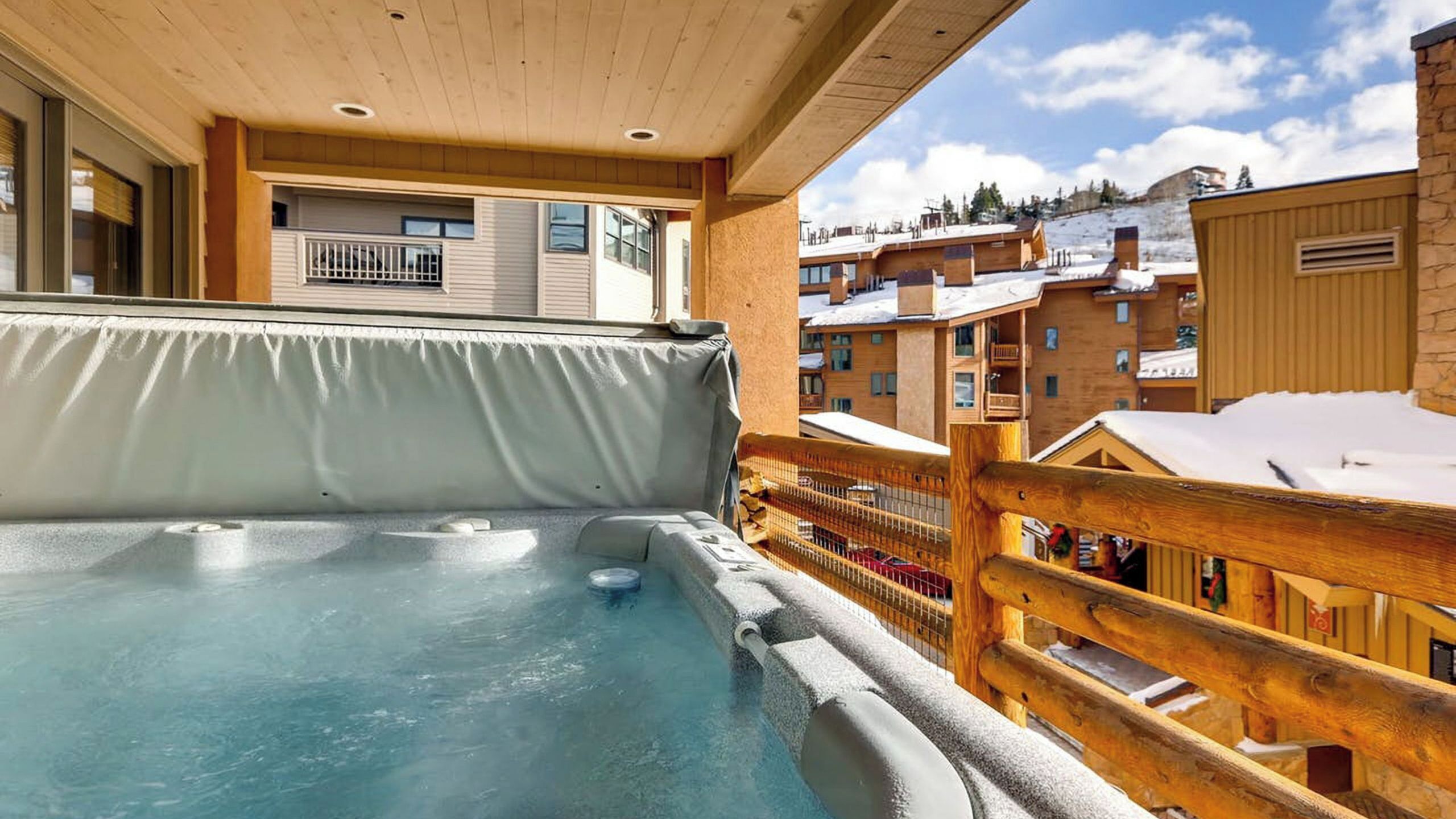 Un bain à remous sur un balcon avec vue sur des bâtiments enneigés.
