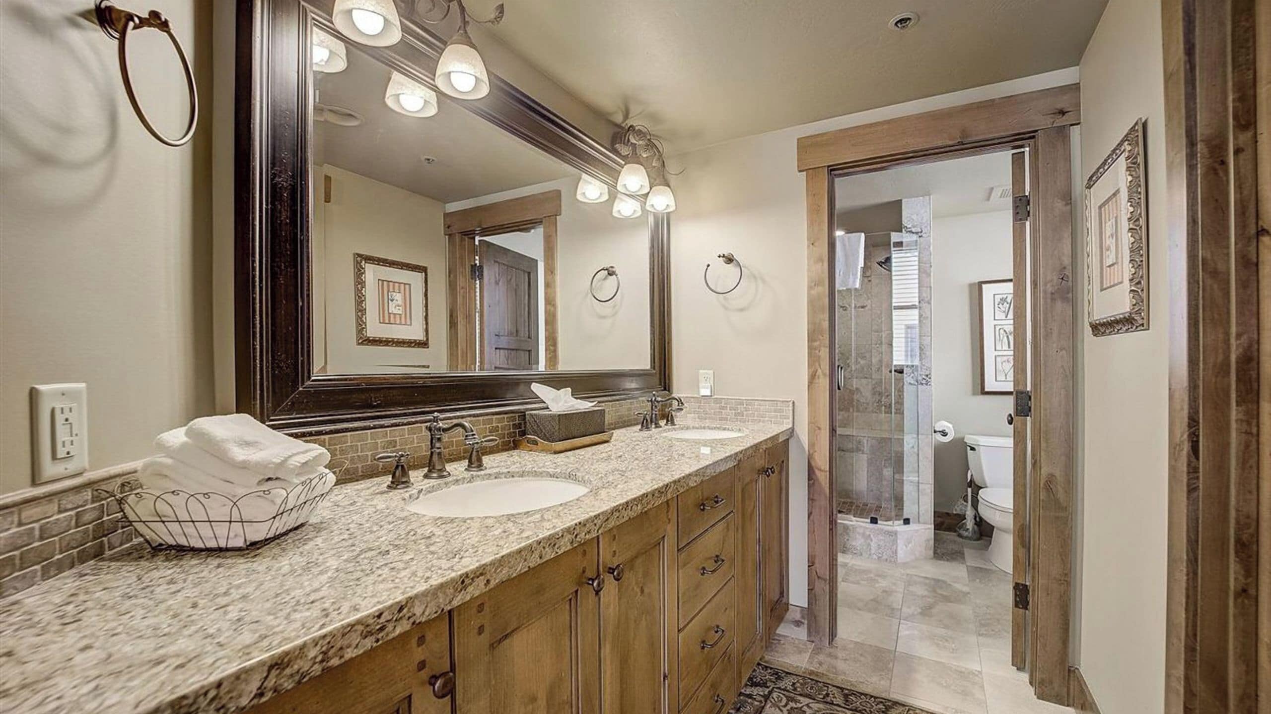 A bathroom with a double sink, a large mirror, and a shower area.