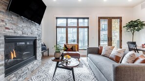 A living room with a fireplace, a sofa, a coffee table, and a large window with a city view. - Kokopelli by Avantstay Close to the Ski Slopes in This Majestic Home in Park City (Park City)